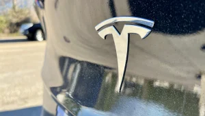 Tesla-Logo in Nahaufnahme auf schwarzer Motorhaube – Symbolbild für Tesla Radio, DAB+ und Streaming statt UKW.